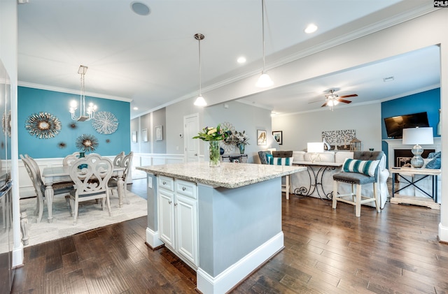 kitchen with white cabinets, light stone counters, dark wood-style flooring, and a center island