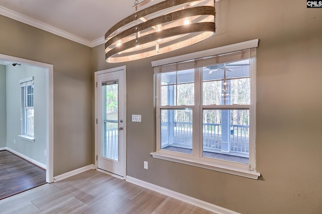 entryway featuring crown molding, wood finished floors, baseboards, and ceiling fan