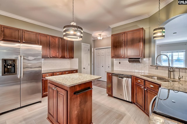 kitchen with light stone countertops, a sink, hanging light fixtures, stainless steel appliances, and crown molding