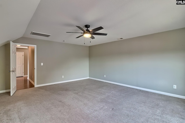 carpeted empty room with visible vents, baseboards, lofted ceiling, and ceiling fan