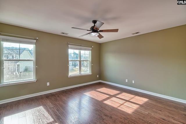 spare room featuring visible vents, dark wood-type flooring, and a healthy amount of sunlight