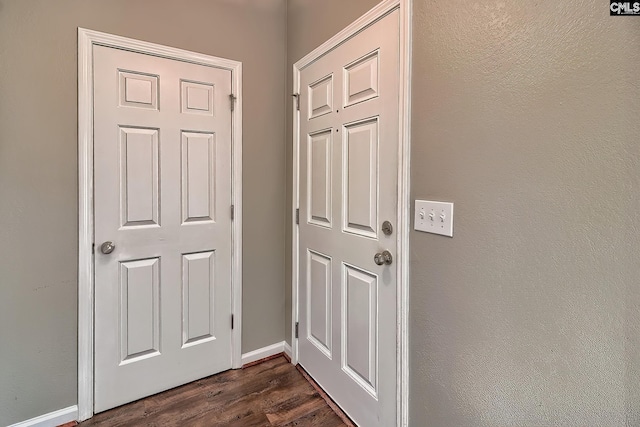 doorway to outside featuring baseboards and dark wood-type flooring