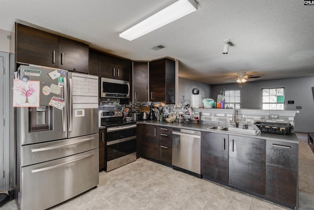 kitchen with dark brown cabinetry, visible vents, stainless steel appliances, and a sink