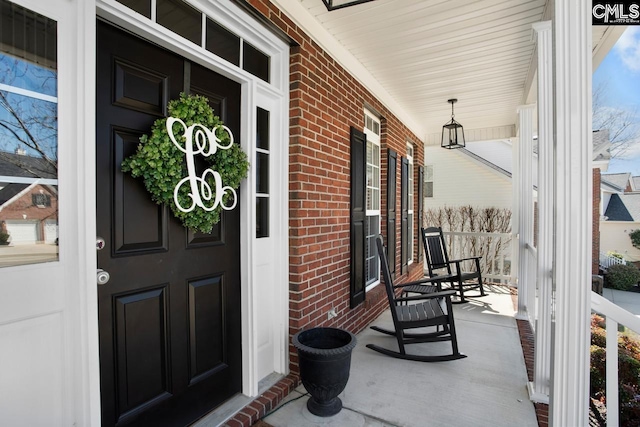 property entrance with brick siding and a porch