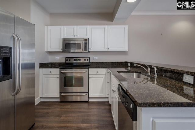 kitchen with a peninsula, a sink, dark wood-type flooring, appliances with stainless steel finishes, and white cabinetry