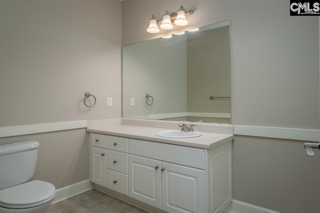 half bath with tile patterned floors, toilet, vanity, and baseboards