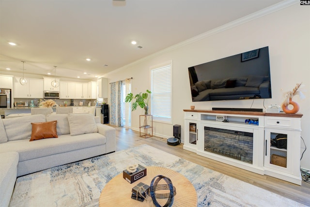 living area with recessed lighting, light wood-type flooring, crown molding, and baseboards