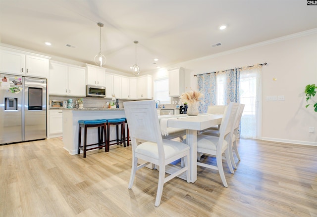 dining space with a healthy amount of sunlight, crown molding, and light wood-type flooring