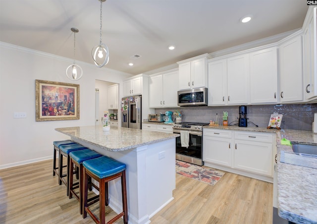 kitchen with light wood-type flooring, a center island, white cabinetry, appliances with stainless steel finishes, and decorative backsplash