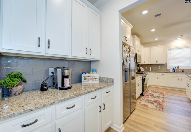 kitchen with visible vents, light wood-style flooring, appliances with stainless steel finishes, and white cabinets