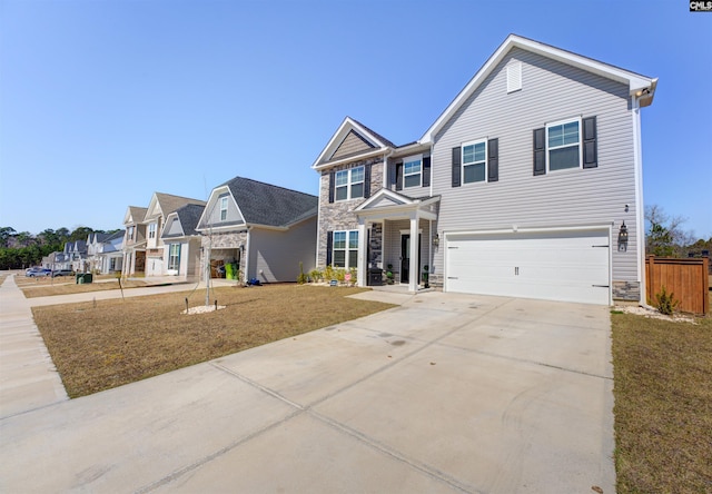 view of front of house with an attached garage, fence, stone siding, and driveway