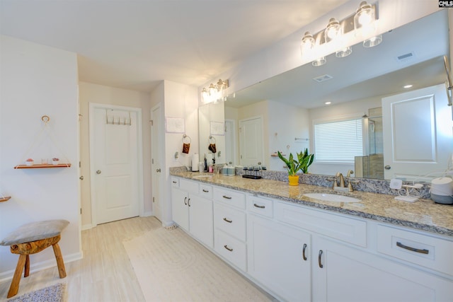 bathroom with a sink, baseboards, a stall shower, and double vanity