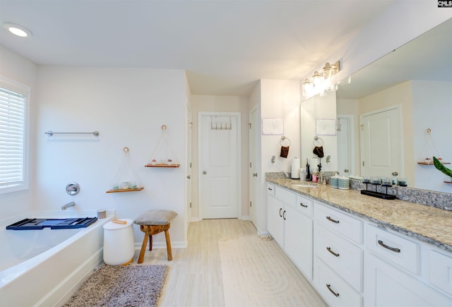 bathroom featuring a bath, vanity, and baseboards