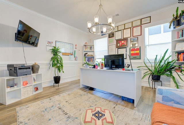 office space featuring light wood-style floors, a wainscoted wall, a notable chandelier, and ornamental molding