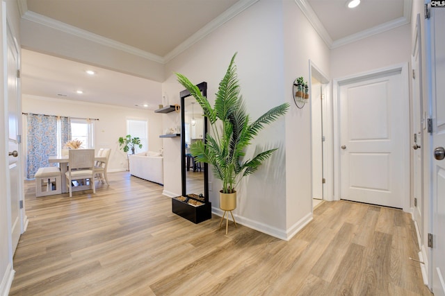 hallway featuring recessed lighting, baseboards, crown molding, and light wood finished floors