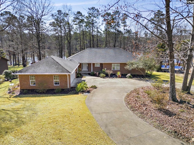 ranch-style home featuring a front lawn, brick siding, roof with shingles, and driveway