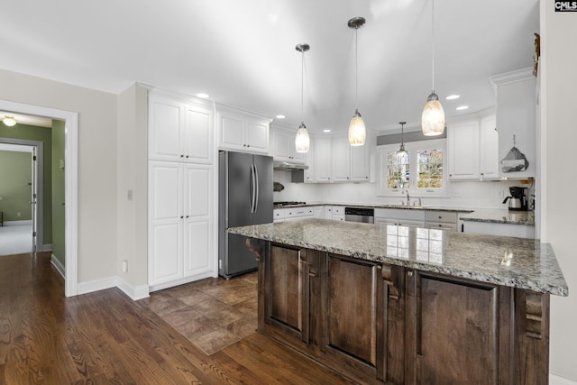 kitchen with a sink, a kitchen island, appliances with stainless steel finishes, white cabinets, and dark wood-style flooring