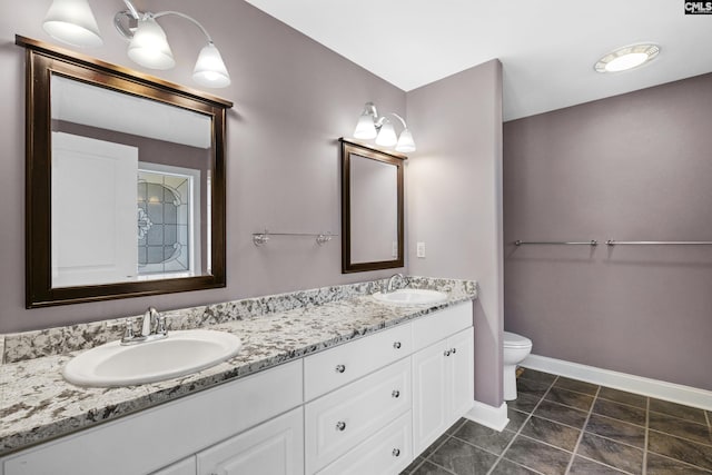 bathroom featuring a sink, baseboards, toilet, and double vanity