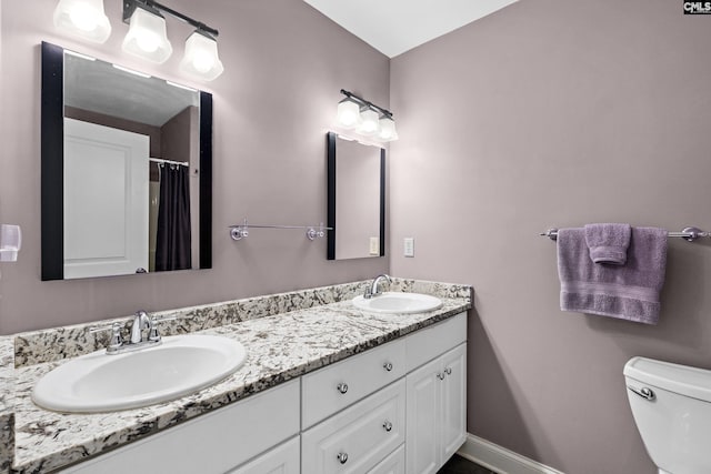 full bath featuring a sink, baseboards, toilet, and double vanity