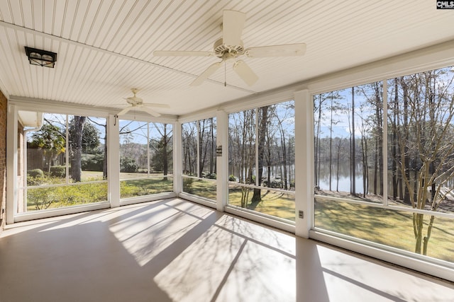 unfurnished sunroom featuring a ceiling fan, a healthy amount of sunlight, and a water view