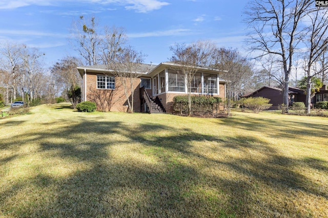 view of front of property with a front lawn, stairway, brick siding, and a sunroom