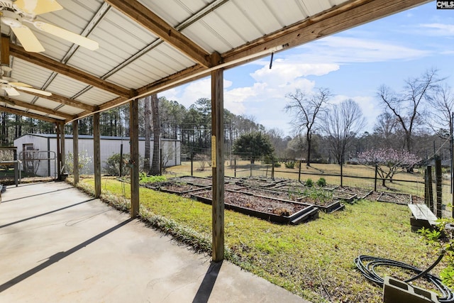 exterior space with a storage unit, an outbuilding, fence, a garden, and ceiling fan