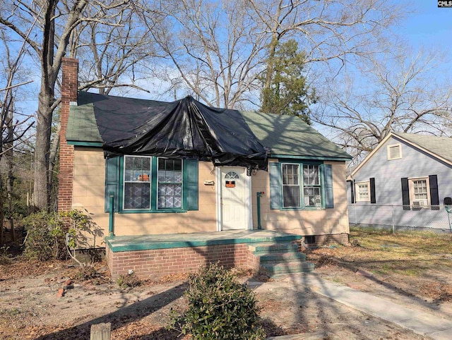 view of front of home with crawl space, a chimney, and fence