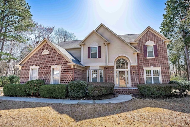 traditional-style home featuring brick siding and a shingled roof