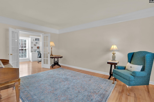 living area with french doors, baseboards, wood finished floors, and ornamental molding