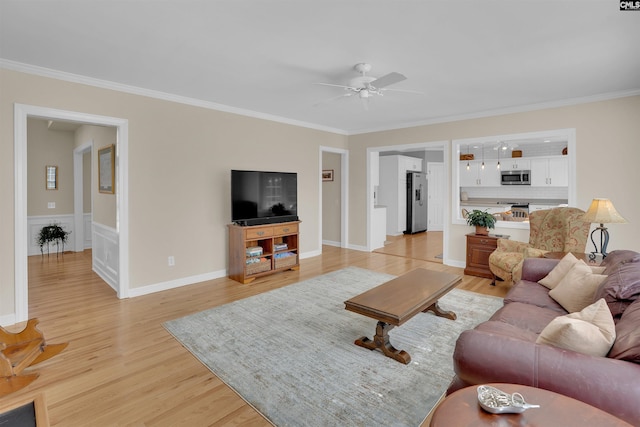 living room featuring ornamental molding, light wood-type flooring, and ceiling fan