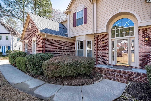 property entrance with brick siding and roof with shingles