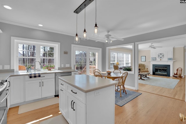 kitchen featuring light wood finished floors, a center island, crown molding, stainless steel appliances, and a ceiling fan