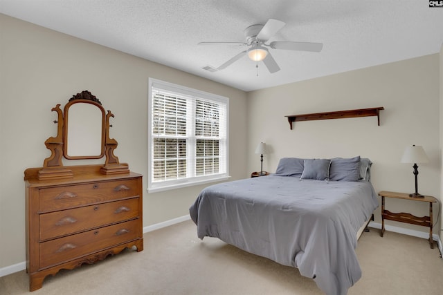 bedroom with light colored carpet, a textured ceiling, baseboards, and ceiling fan