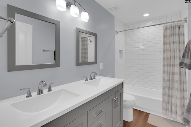 bathroom with a sink, visible vents, shower / tub combo with curtain, and wood finished floors