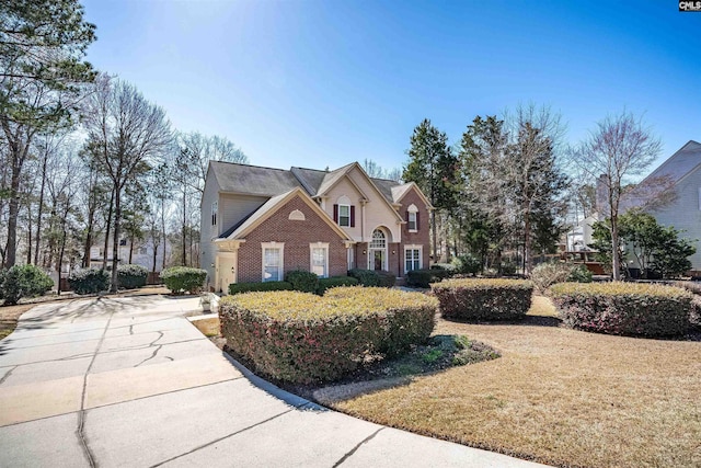 traditional-style home featuring brick siding and a front yard