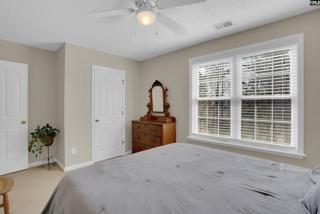 carpeted bedroom featuring visible vents, a textured ceiling, baseboards, and a ceiling fan