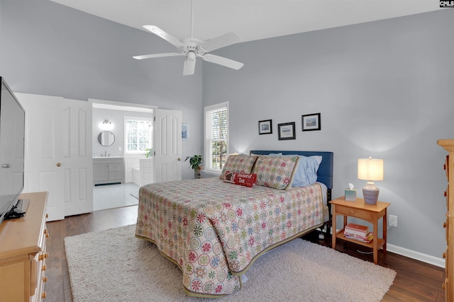 bedroom featuring high vaulted ceiling, a ceiling fan, ensuite bath, wood finished floors, and baseboards