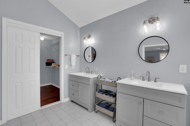 bathroom with a sink, two vanities, tile patterned floors, and vaulted ceiling