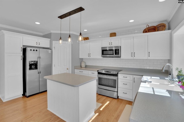 kitchen featuring a sink, appliances with stainless steel finishes, white cabinetry, crown molding, and light wood-type flooring