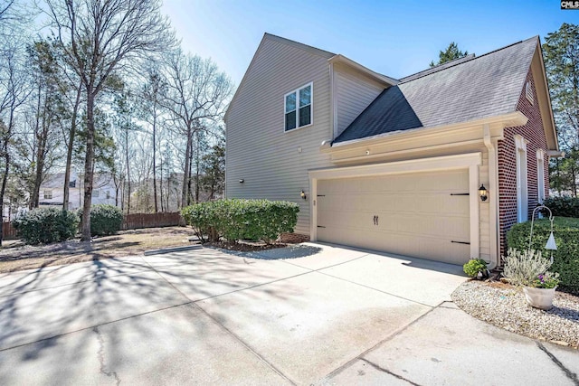 view of home's exterior with a garage, brick siding, driveway, and roof with shingles