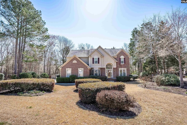 traditional-style home featuring brick siding and a front lawn