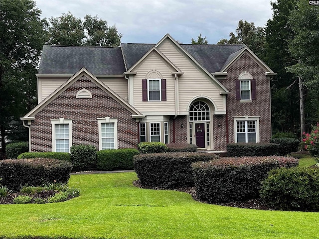 traditional home with a front yard and brick siding