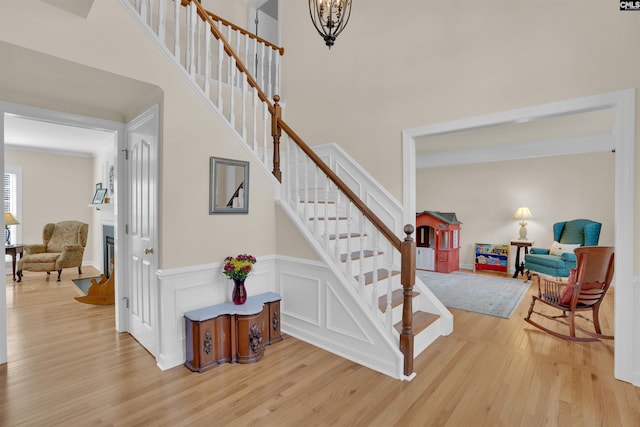 stairs with a glass covered fireplace, ornamental molding, a high ceiling, and wood finished floors