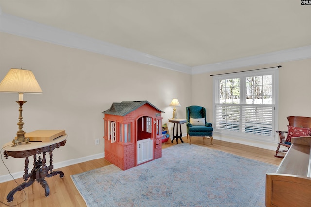 living area featuring crown molding, wood finished floors, and baseboards