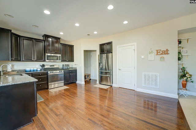 kitchen featuring visible vents, stainless steel appliances, wood finished floors, and a sink