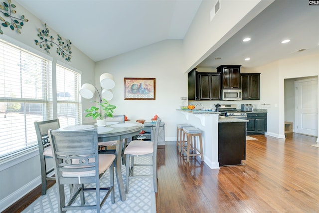 dining space featuring vaulted ceiling, wood finished floors, and baseboards