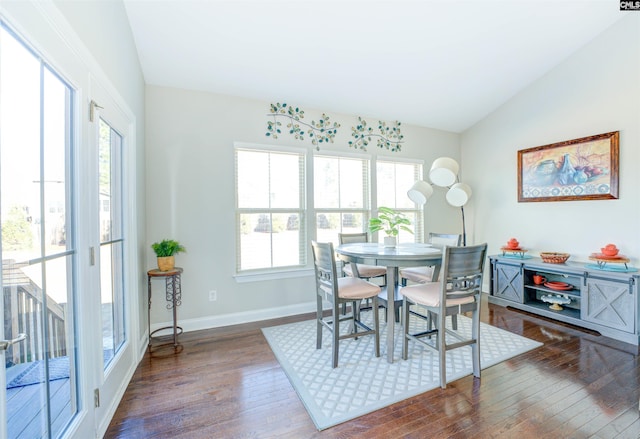 dining area featuring vaulted ceiling, hardwood / wood-style flooring, and baseboards