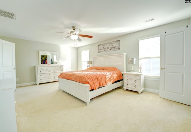 bedroom with visible vents, multiple windows, and light carpet