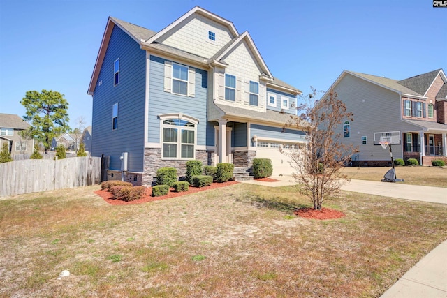 craftsman house featuring fence, concrete driveway, a front lawn, a garage, and stone siding