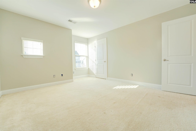 spare room featuring visible vents, baseboards, and light colored carpet